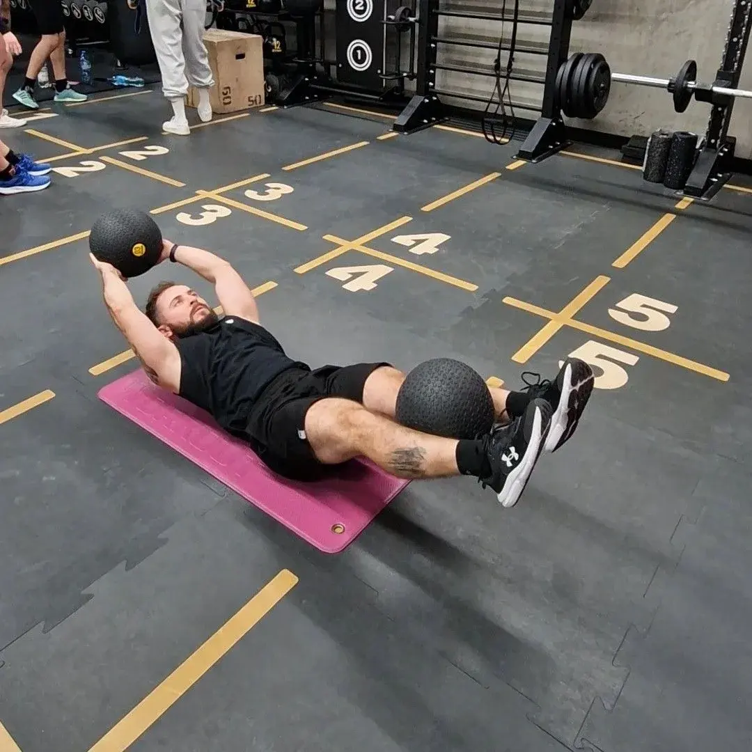 Trening mięśni brzucha z piłką lekarską na sali Xtreme Fitness